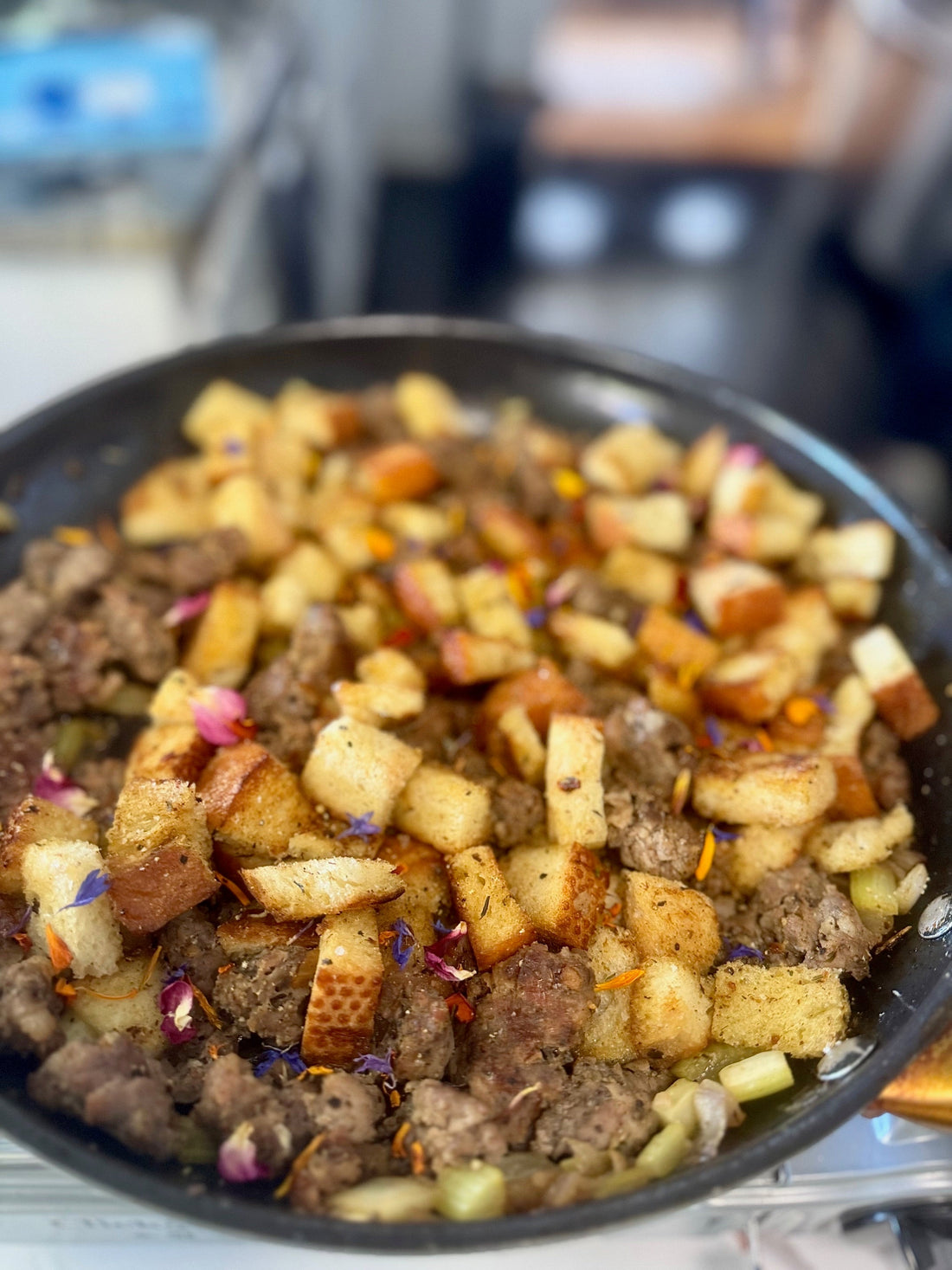 Image of a skillet with sauage stiffing topped with edible flowers