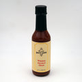 A bottle of Hot Ones Hot Sauce Whiskey Smoked Ghost flavor with a label featuring the product name andUncle Nearest Whiskey branding.
